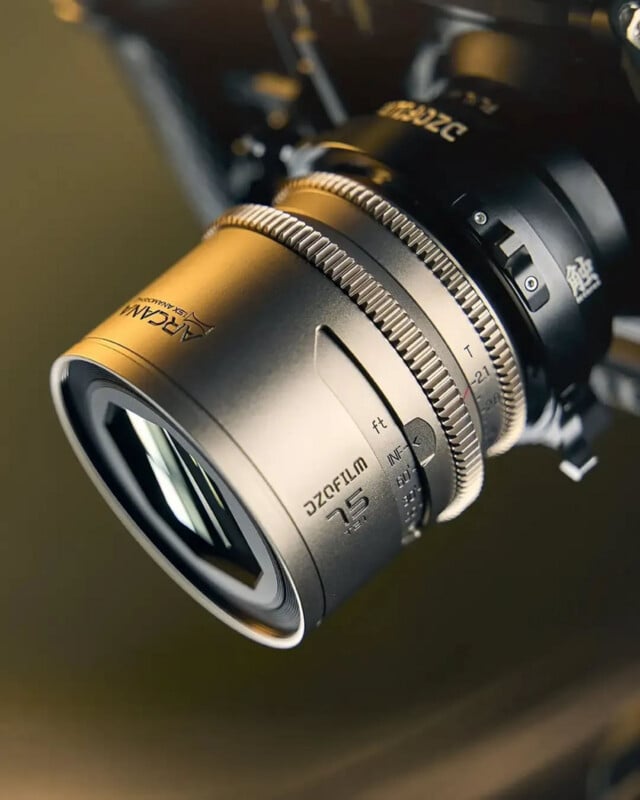 Close-up of a silver ARCAM DZOFilm camera lens with a 75mm focal length, showing detailed focus and aperture markings, attached to a camera body.