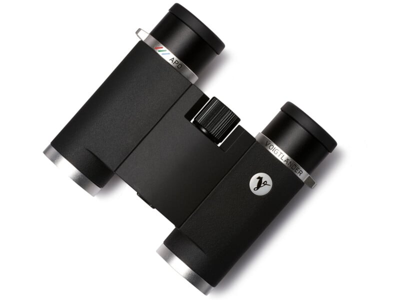 A pair of compact black binoculars with metallic silver accents and a central focus wheel, featuring the brand name "Voigtländer" and a small logo on one barrel.