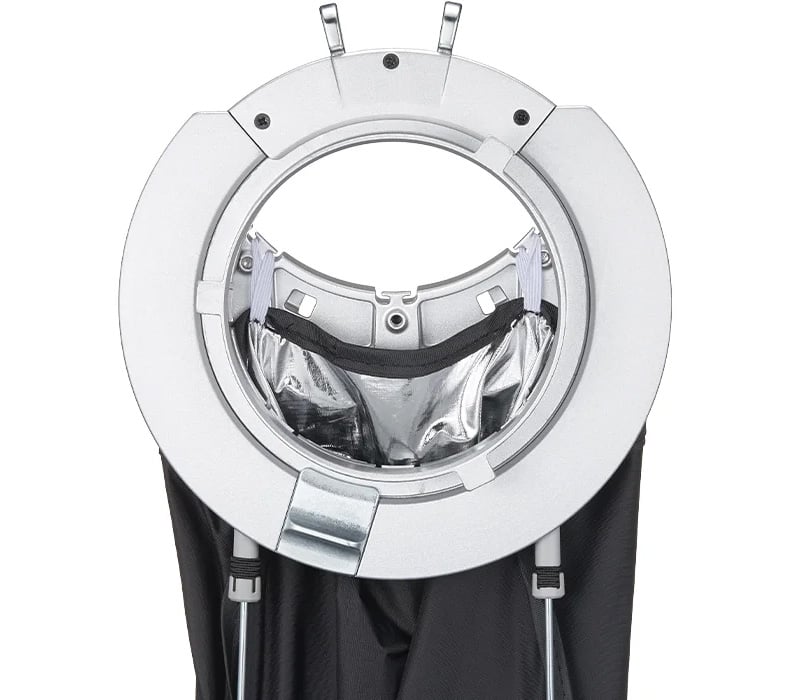 A close-up view of a silver circular device holding a reflective, metallic pouch, with black fabric straps hanging down from it.