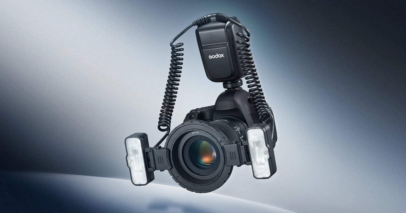 A DSLR camera with a mounted Godox ring flash and dual LED lights attached to the lens, set against a gradient blue and gray background.
