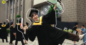 A joyful graduate in cap and gown poses playfully with one arm raised and one leg outstretched. Other graduates and people are in the background. White outlines and Chinese text highlight the person's arm and leg.