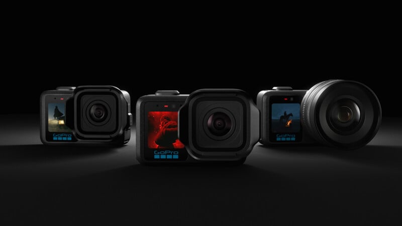 Four GoPro cameras are arranged side by side on a dark surface, each displaying different action scenes on their screens. The cameras are lit dramatically, highlighting their lenses and compact design.