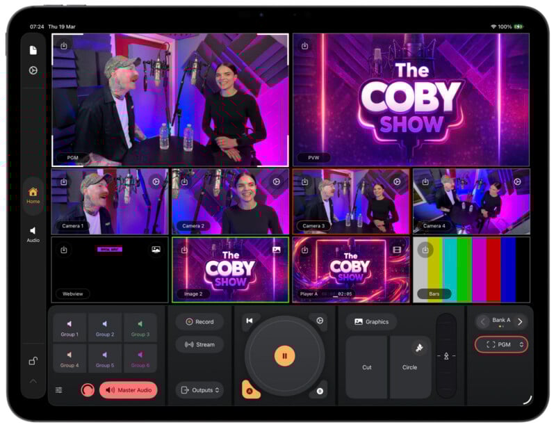 A tablet screen displays a video production interface with multiple camera angles of two people talking in a purple-lit studio for "The Coby Show." The main camera feed shows both hosts behind microphones.