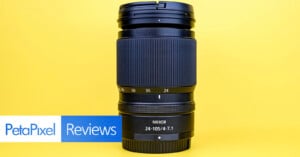 A Nikon Nikkor 24-105mm f/4-7.1 camera lens stands upright against a bright yellow background, with a "PetaPixel Reviews" banner in the lower left corner.