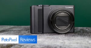 A black Lumix digital camera with a Leica lens is displayed on a gray surface against a green background. The image includes "PetaPixel Reviews" text in the bottom left corner.
