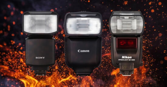 Three camera flashes—Sony, Canon, and Nikon—are displayed upright side by side against a dark background with dramatic orange flames rising beneath and behind them.