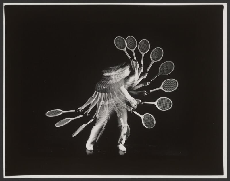 A black and white photo shows a tennis player in motion, captured multiple times in one image. The overlapping frames create a visual effect of several rackets and body positions against a dark background.
