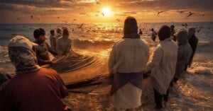 A group of fishers in head coverings stand in shallow water, pulling in a large net at sunrise or sunset, with seagulls flying over the waves and golden light reflecting on the sea’s surface.