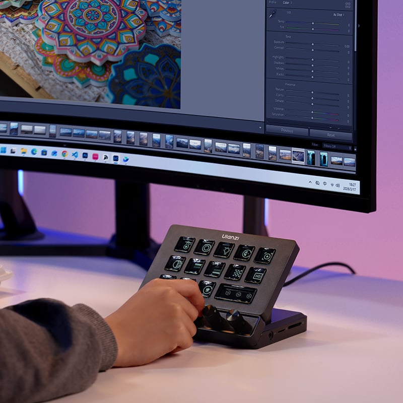 A person uses a Loupedeck control panel in front of a curved computer monitor displaying photo editing software with a colorful patterned image on the screen.