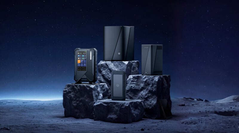 Four sleek, black tech devices are displayed on rocky pedestals, set against a starry night sky and a moon-like surface, creating a futuristic and high-tech atmosphere.