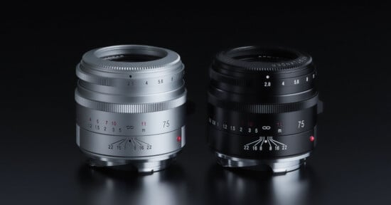 Two camera lenses are displayed side by side on a black surface, one in silver and one in black. Both lenses have similar designs, with aperture and focus markings and the number “75” visible on the front.