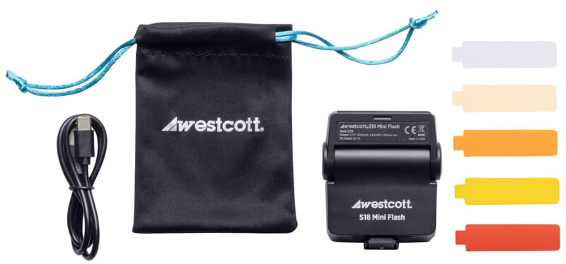 A Westcott S1B Mini Flash kit with a black drawstring pouch, USB cable, mini flash unit, and five color gel filters in white, light orange, orange, yellow, and red.