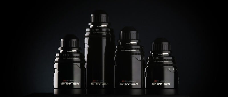 Four black XELMÁUS branded electronic devices of varying heights are arranged in a row against a dark background, with reflective surfaces highlighting their sleek, cylindrical designs.