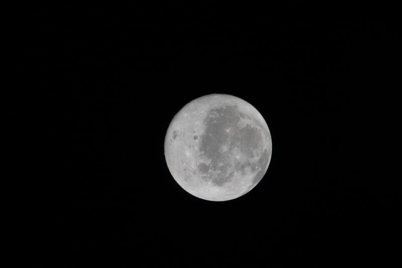 A bright full moon is centered against a black night sky, with visible craters and surface details.