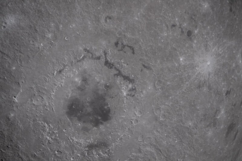 Close-up image of the Moon’s surface, showing detailed craters and dark, shadowy maria areas with varying textures and shades of gray.