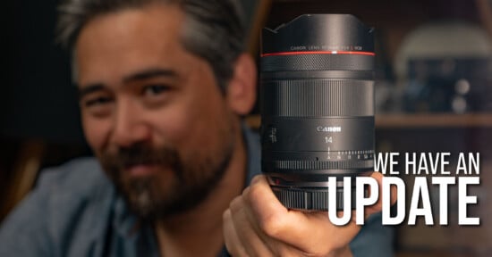 A person with salt-and-pepper hair holds a Canon 14mm camera lens toward the camera. The text "WE HAVE AN UPDATE" appears prominently on the right side of the image.
