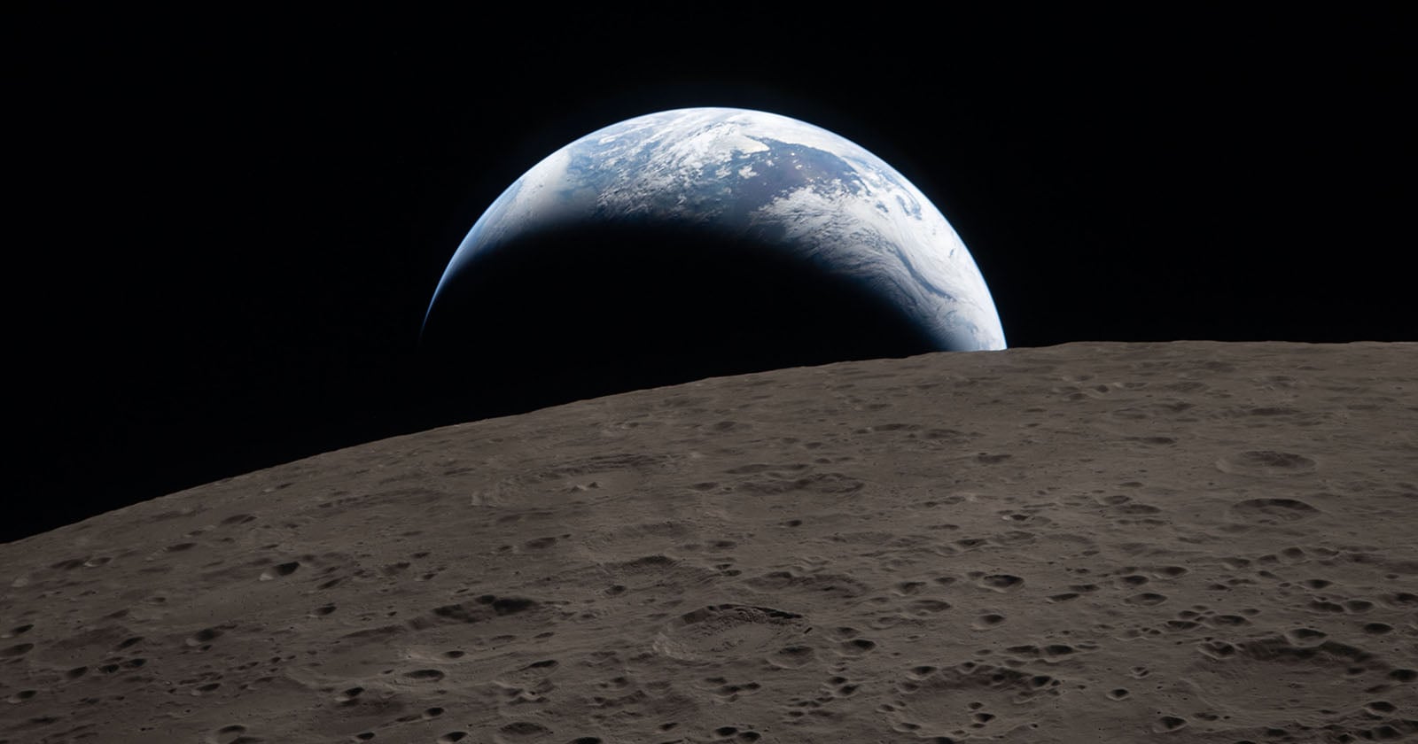 A view of Earth rising above the Moon’s cratered surface, showing a curved horizon and Earth's blue and white colors against the blackness of space.
