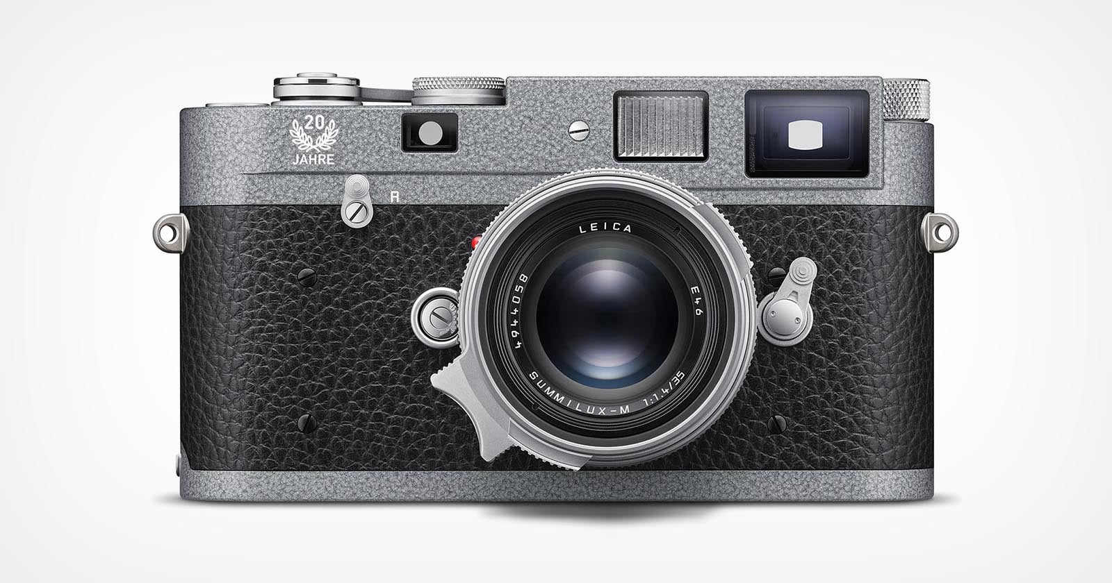 A silver and black Leica camera with a textured grip, prominent lens, viewfinder, and dials is positioned against a plain white background. The camera features a “20 Jahre” marking near the top left.
