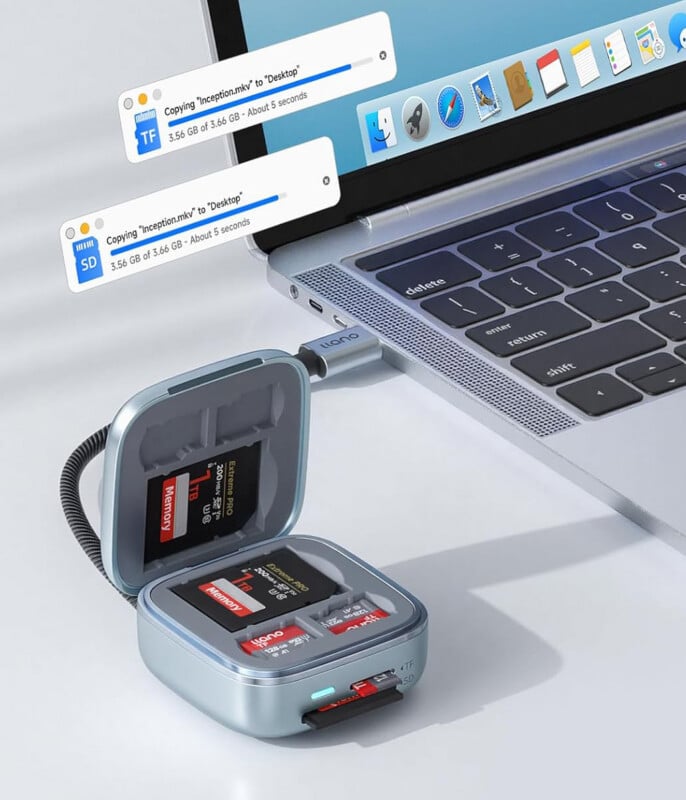 A laptop with a card reader case connected via USB-C. The case holds several SD and microSD cards, with one card inserted. On the screen, file transfer progress bars show data being copied.