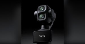 A close-up of a black DJI Osmo camera with dual lenses and a gimbal mount, shown against a dark background. The device has the word "OSMO" displayed on its front panel.