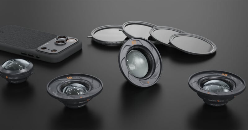 Four camera lenses, three round lens filters, and a smartphone with a textured back are arranged on a dark surface, showcasing photography accessories in a neat layout.