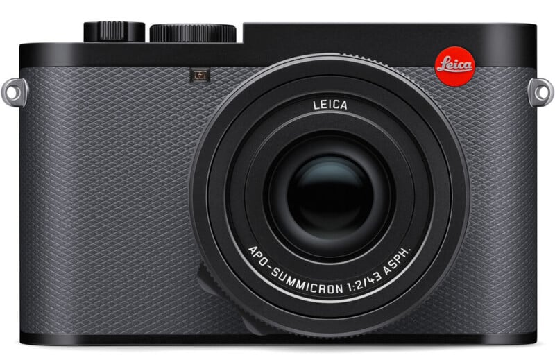 Front view of a black Leica digital camera with a textured body, prominent lens, and red Leica logo on the upper right side.
