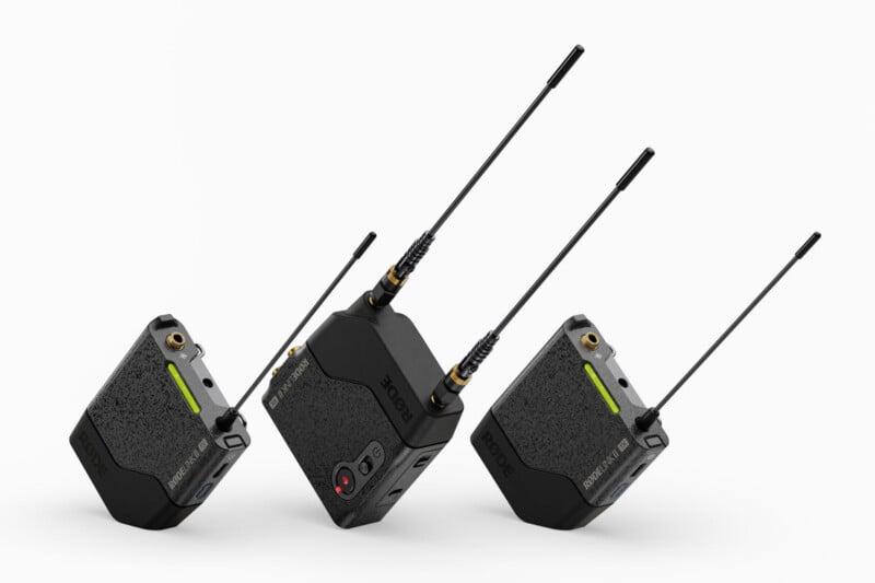 Three black wireless audio transmitters with antennas are positioned upright on a white background. Each device features a textured surface, visible ports, indicator lights, and branding that reads "RODE.