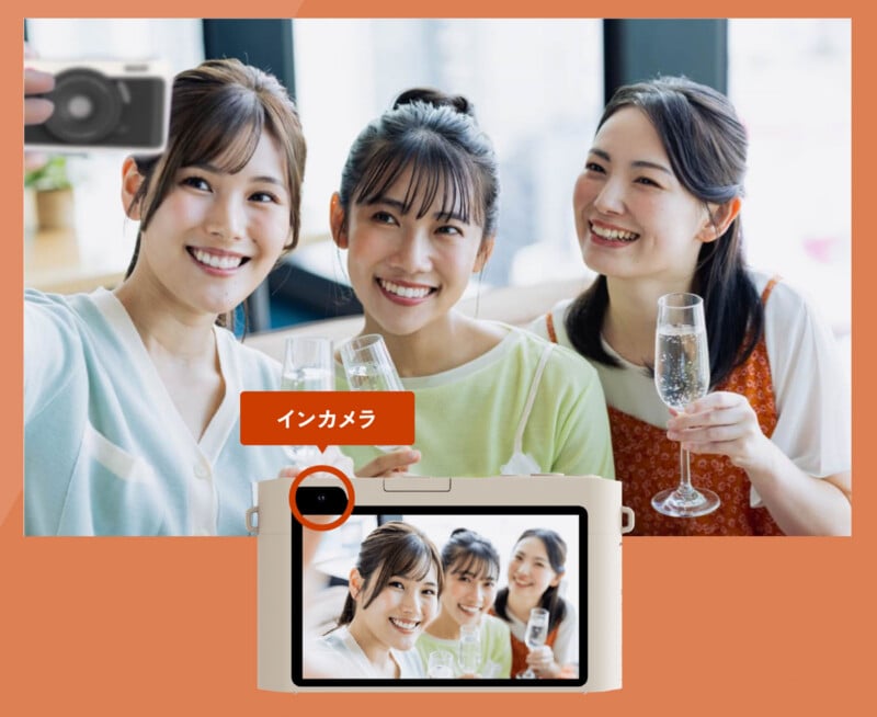 Three young women smiling and holding drinks while taking a selfie together, with a camera interface displaying their photo in the foreground. An orange label with Japanese text points to the camera's lens.