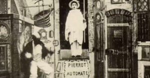 A vintage black-and-white image shows a mechanical man in white costume standing in a box labeled "Pierrot Automate," surrounded by gears and strange machinery, while another person moves energetically beside the box.