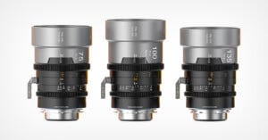 Three professional camera lenses with silver barrels are displayed upright side by side. Each lens has focal lengths labeled 75mm, 100mm, and 135mm, along with various aperture and focus markings.