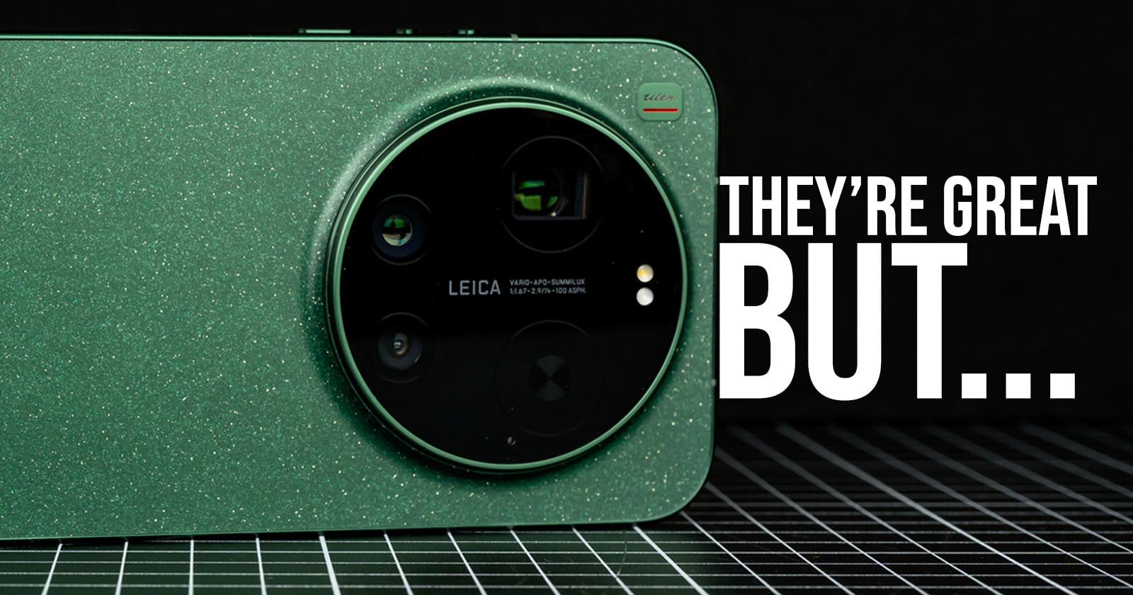 Close-up of a green smartphone with a large circular Leica camera module. Text on the right reads, "THEY'RE GREAT BUT..." against a black grid background.