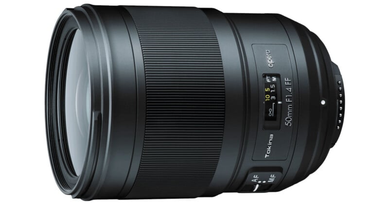 Vista en primer plano del objetivo de la cámara Tokina Opera 50 mm f/1,4 FF, que muestra su anillo de enfoque, su interruptor de enfoque automático/manual y su escala de distancia sobre un fondo blanco.