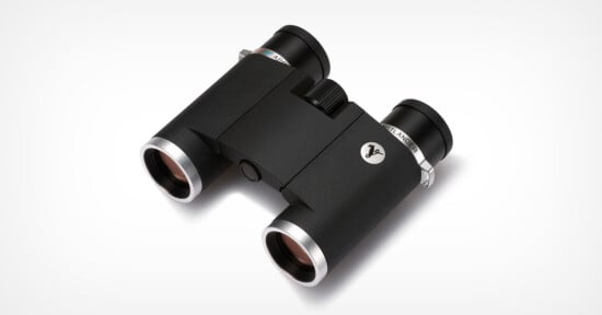 A pair of compact black binoculars with silver accents, viewed at an angle from above, against a white background.