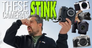 A man holds his nose in disgust while holding a camera. Large text reads "These Cameras Stink," surrounded by images of various cameras and camera lenses on a bright background.