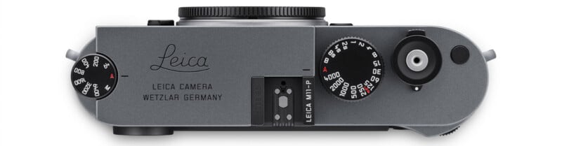 Top view of a silver Leica M11-P camera showing the engraved Leica logo, control dials, shutter button, and "LEICA CAMERA WETZLAR GERMANY" text. The camera body is sleek and minimalist in design.