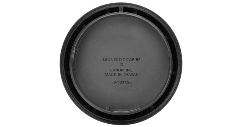 A close-up view of a Canon lens dust cap RF II, showing the text “LENS DUST CAP RF II CANON INC. MADE IN TAIWAN >PC-GF30<” embossed on the inside surface.