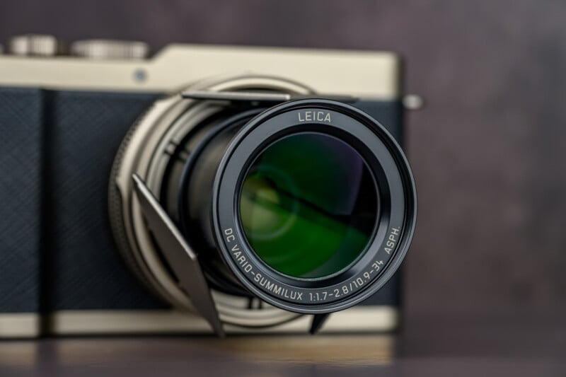 Close-up view of a Leica camera lens with "DC VARIO-SUMMILUX 1:1.7-2.8/10.9-34 ASPH." written around the rim, attached to a camera body with a textured black and silver finish.