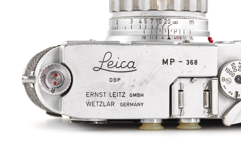 Top view of a vintage silver Leica camera, showing engraved branding, dials, and controls. The text includes "Leica," "MP–368," and "ERNST LEITZ GMBH WETZLAR GERMANY.