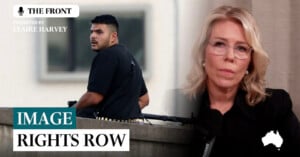 A serious-faced woman with blonde hair and glasses speaks into a microphone. Beside her, a man in black clothing stands behind a barricade holding a large gun. Text reads "IMAGE RIGHTS ROW," "THE FRONT," and "CLAIRE HARVEY.