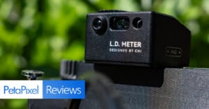 A close-up of an L.D. Meter device designed by CHI mounted on a camera, with the PetaPixel Reviews logo overlaid in the foreground and a blurred green background.