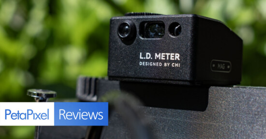 A close-up of an L.D. Meter device designed by CHI mounted on a camera, with the PetaPixel Reviews logo overlaid in the foreground and a blurred green background.