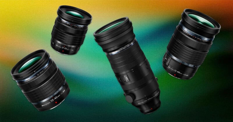 Four professional camera lenses are displayed against a colorful, abstract gradient background with shades of green, yellow, and orange. The lenses are oriented at various angles and feature detailed markings and glass.