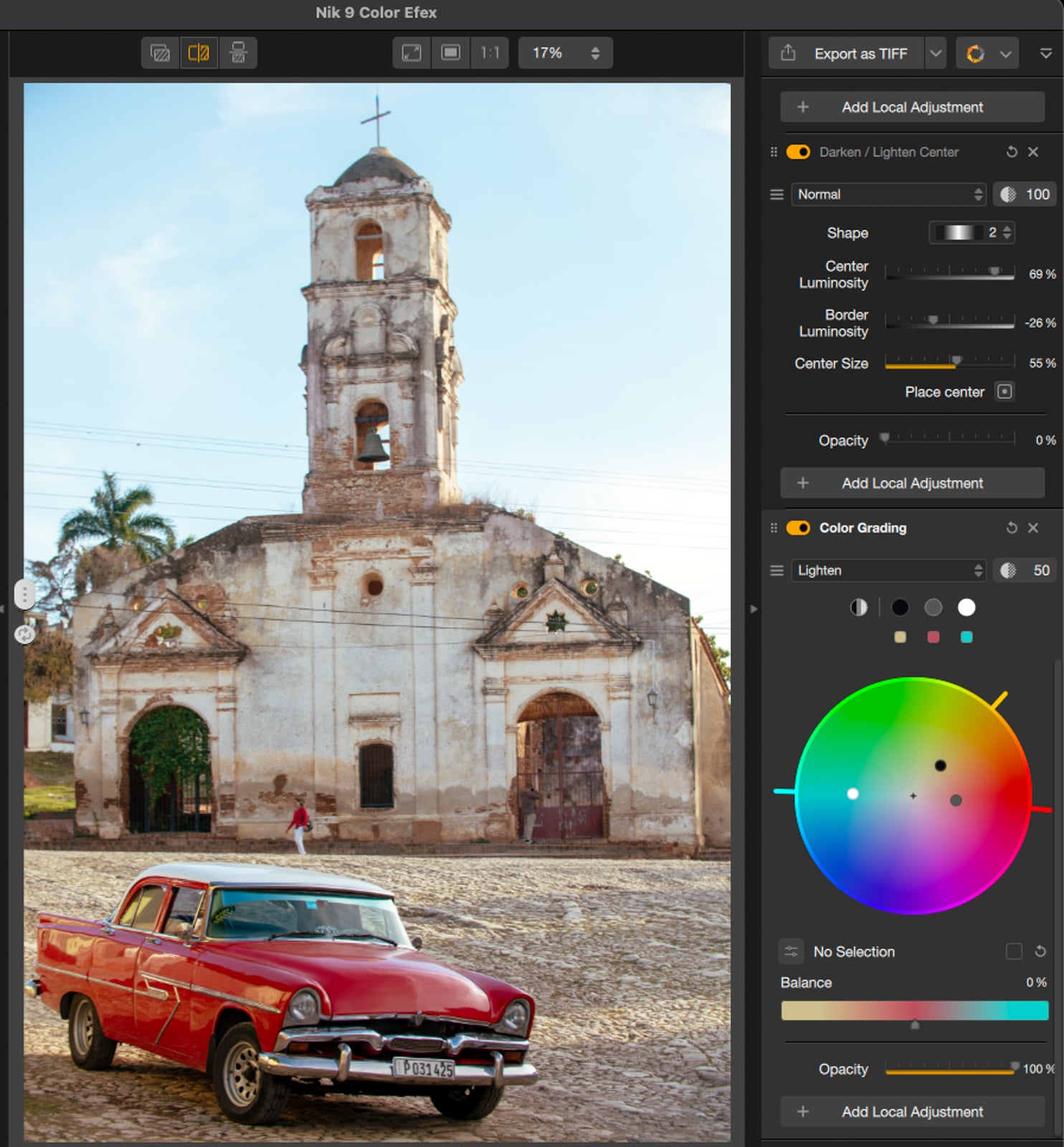 A red vintage car is parked on a cobblestone street in front of an old, weathered church with a bell tower. The image is open in a photo editing software displaying color grading and adjustment tools on the right.