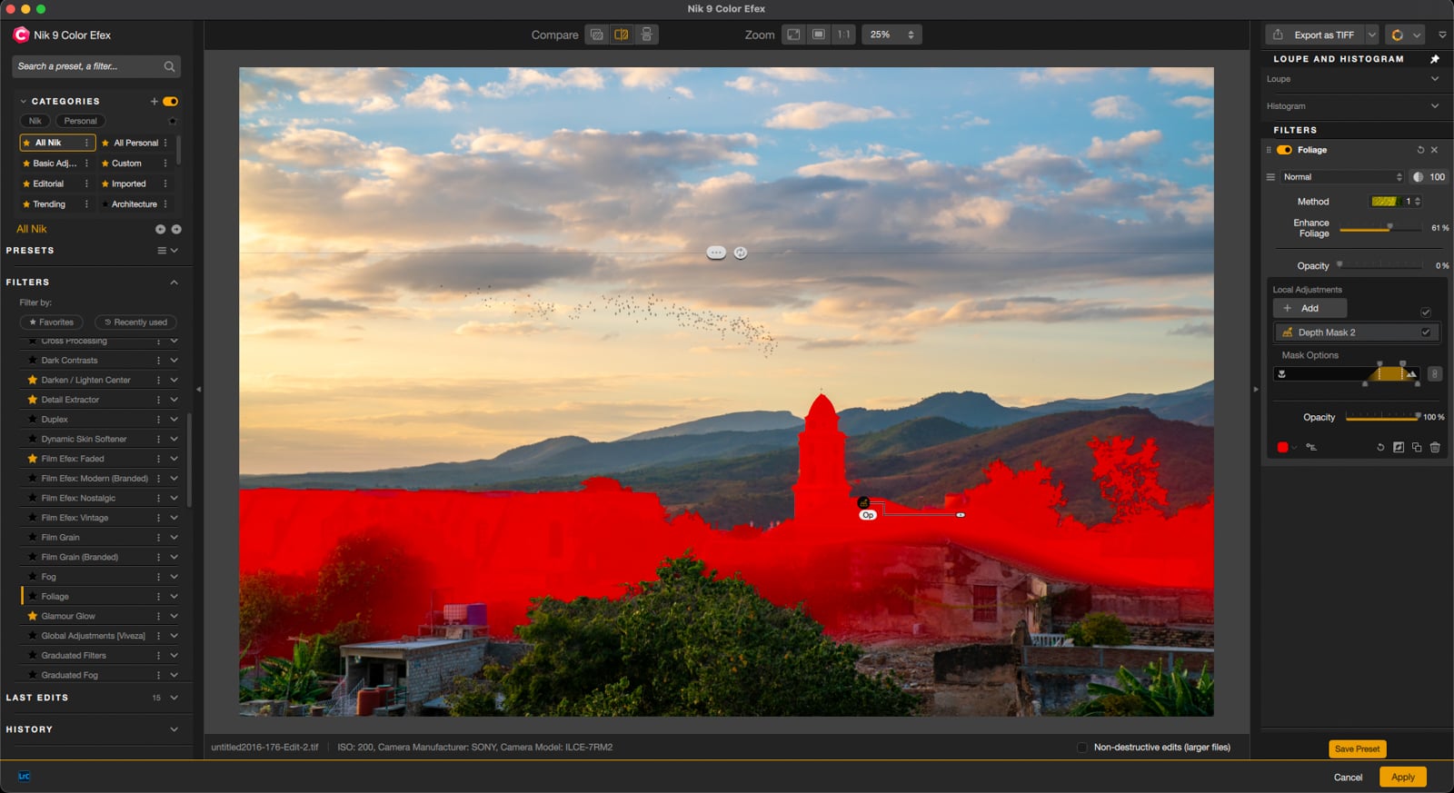 A photo editing software interface shows a landscape image with hills and a cloudy sky. Part of the image, including buildings and trees, is highlighted in red to indicate a selected mask area. Editing tools are visible on the sides.