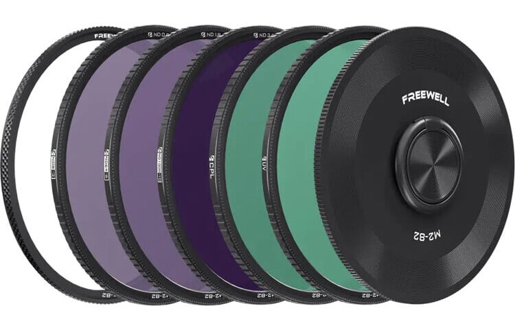 Five circular camera lens filters with black rims, each displaying different tinted glass (purple and green), arranged overlapping in a row. The front filter is labeled "FREEWELL" and "M2-82".