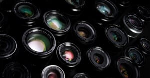 A close-up view of multiple camera lenses arranged closely together, showing various reflections and details of the glass elements in each lens.