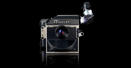 A high-end IMAX KEIGHLEY film camera is displayed against a black background, featuring a large central lens, carbon fiber texture, and an attached viewfinder on the top right.