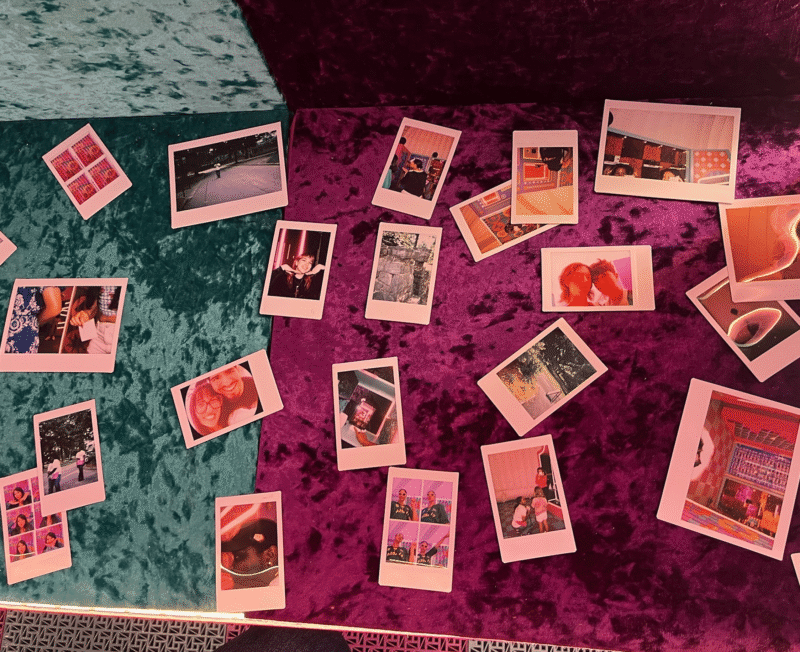 Several instant photos are scattered across a textured surface with teal and purple colors. The photos show people, outdoor scenes, and interiors, capturing various moments and memories.