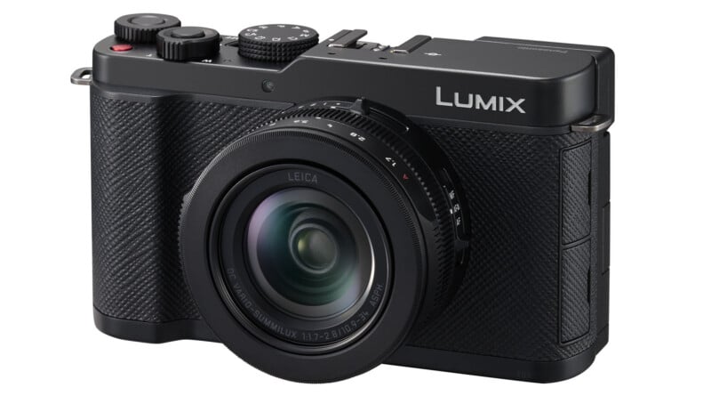 A black Panasonic Lumix digital camera with a Leica lens is shown at an angle, displaying its textured grip, buttons, and dials on the top. The lens is large and prominent in the foreground.