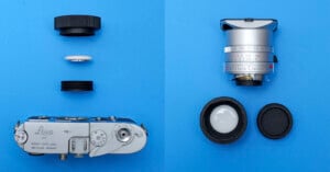 A vintage Leica camera and a silver lens are displayed separately on a blue background, each with their lens caps and accessories neatly arranged around them.
